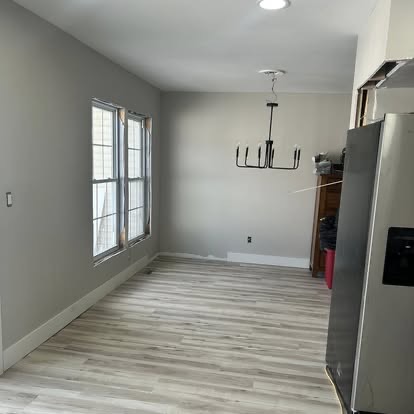 Bright open dining area with new flooring, fresh paint, and a modern chandelier